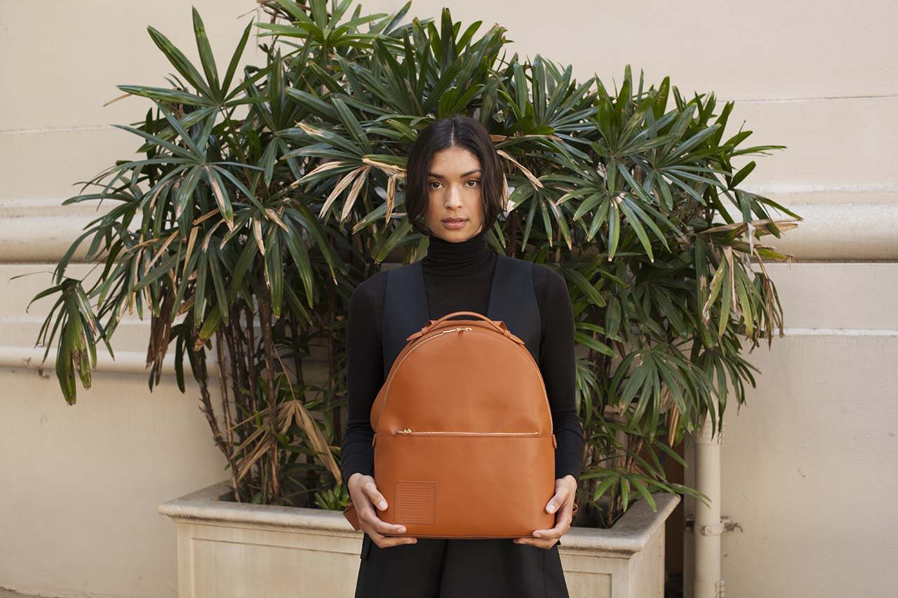 A woman wearing a black dress wearing an Opus Mind orange bagpack