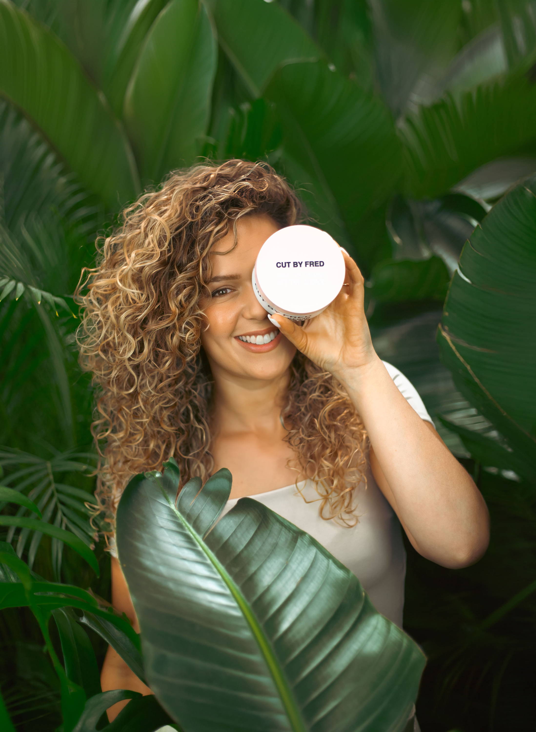 Femme au cheveux bouclés avec un masque dans la main