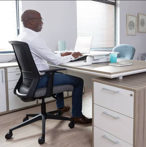 A man sitting at his desk with an ergotherapy office chair that  follows the shape of his spine and gives ergonomic support