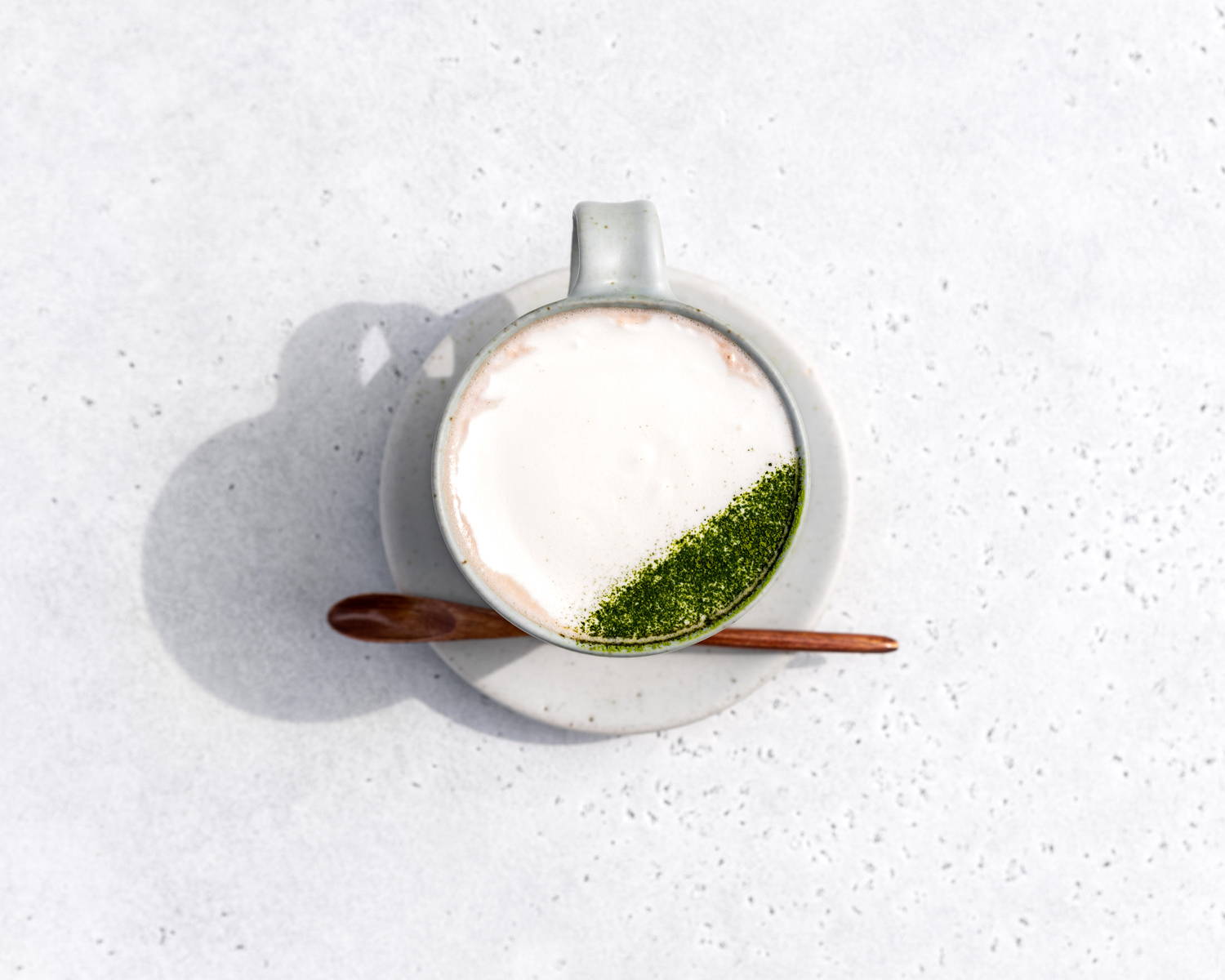 An above view of a matcha hot chocolate with fresh whipped cream and an artistic dusting of matcha powder, by SingleThread.