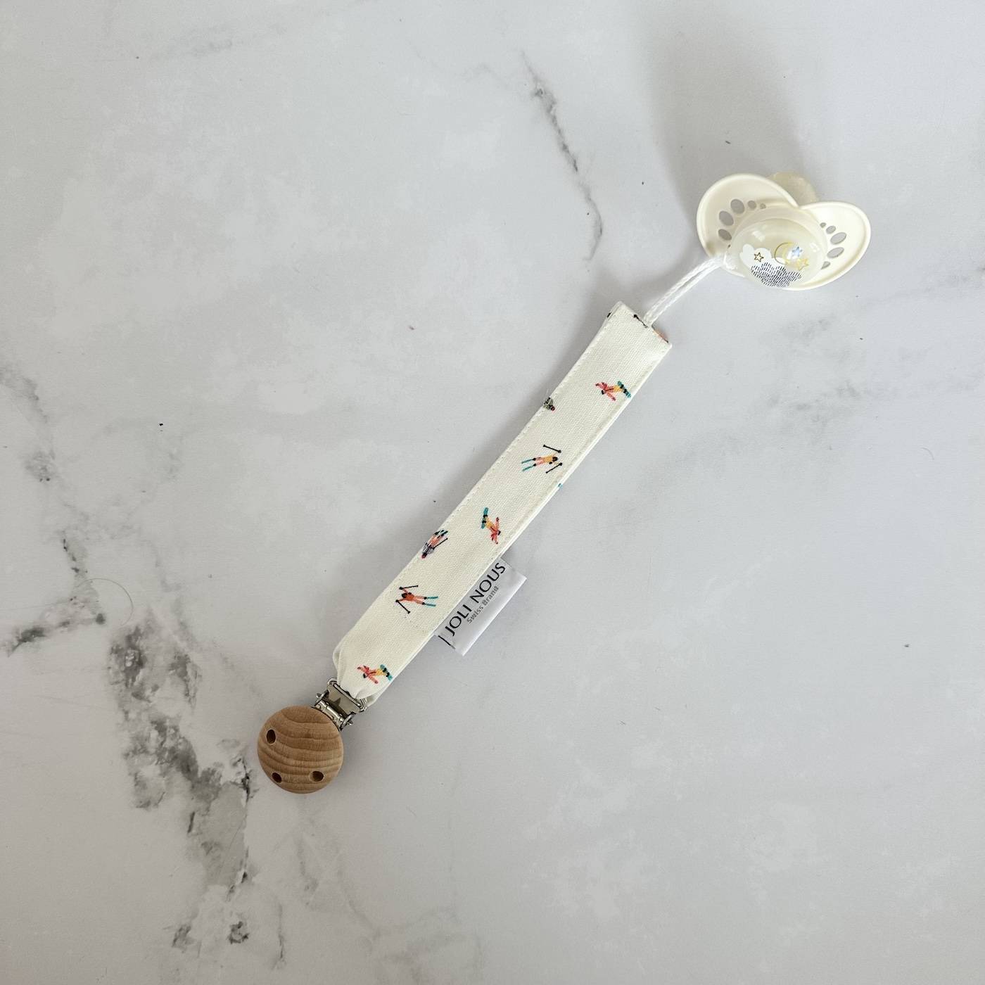 Attache-tétine élégant de la marque suisse 'Joli Nous', un accessoire premium pour bébé, alliant design raffiné et qualité exceptionnelle