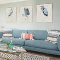 set of three wall art prints above a sofa. three heron prints above a sofa in living room.