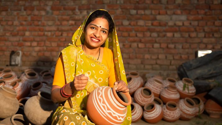 Traditional Indian woman, potter artist, painting and decorating design on clay pot