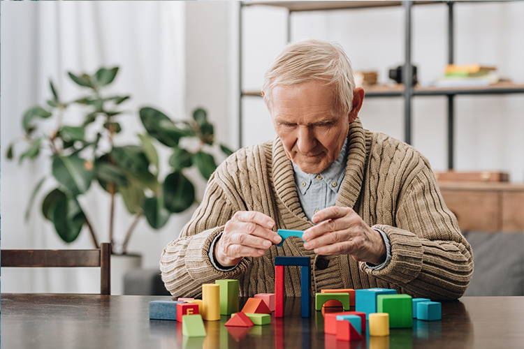 old man playing with building blocks