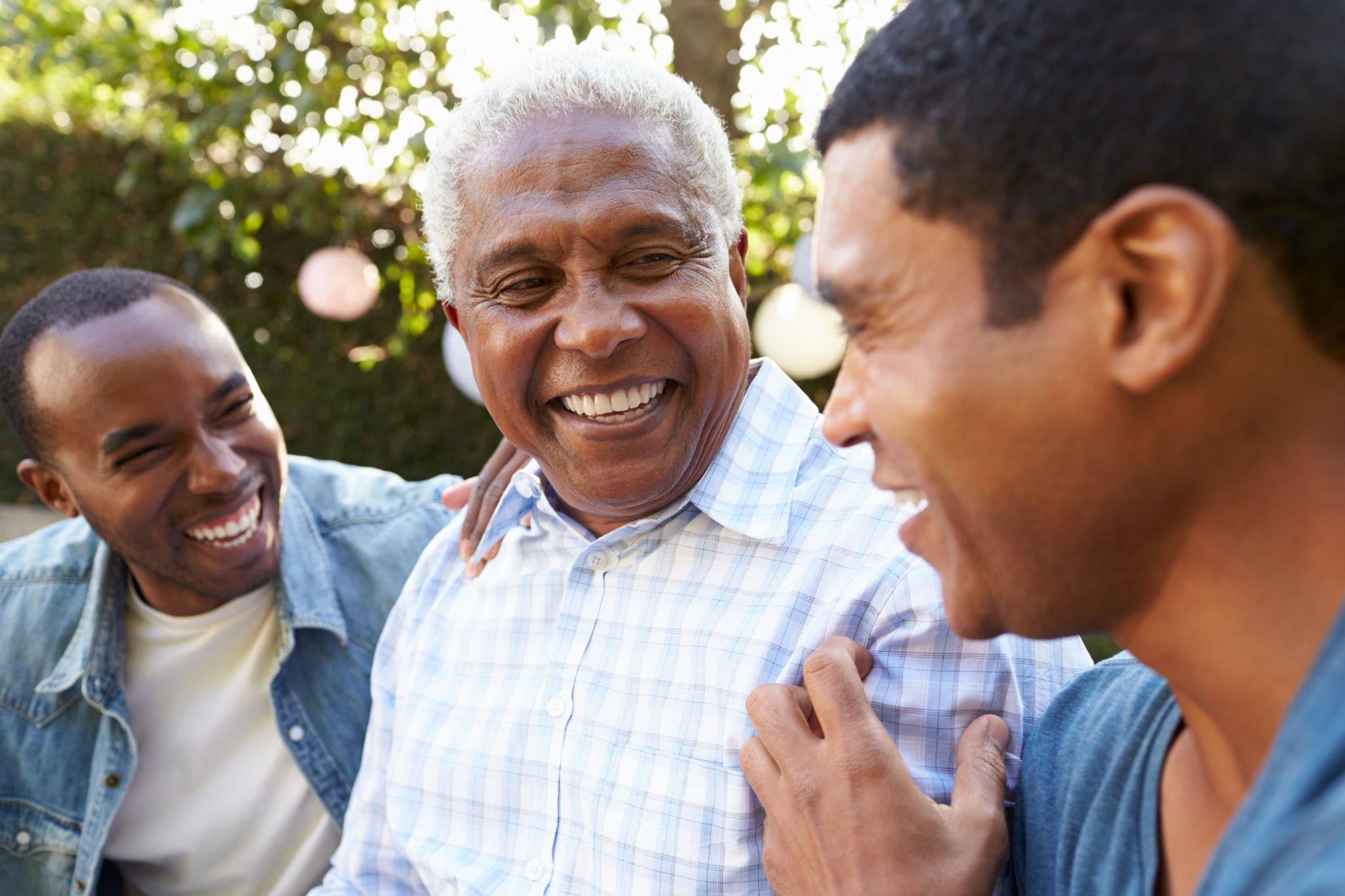 Senior man talking with his adult sons in garden