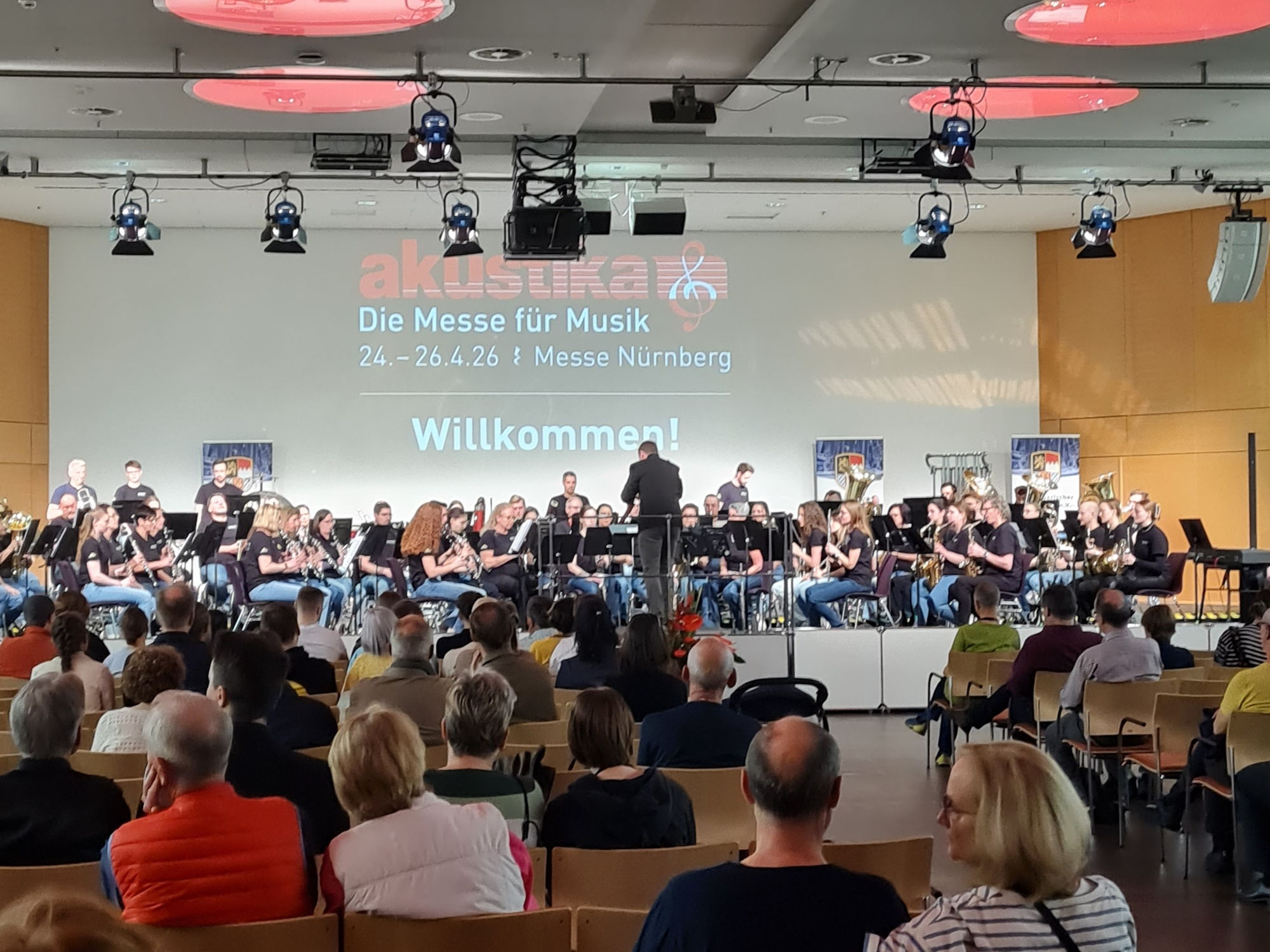 Auf einer Bühne musiziert ein Orchester vor Publikum. 