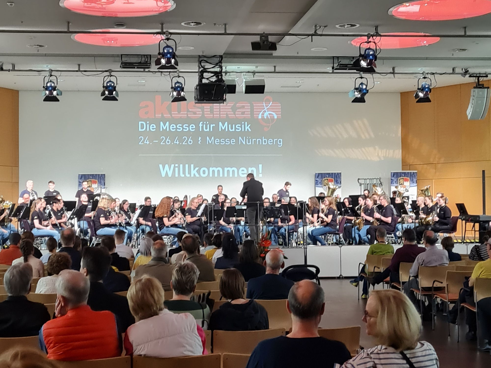 Auf einer Bühne musiziert ein Orchester vor Publikum. 