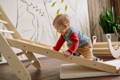 Baby boy climbing the wooden Montessori ladder. 