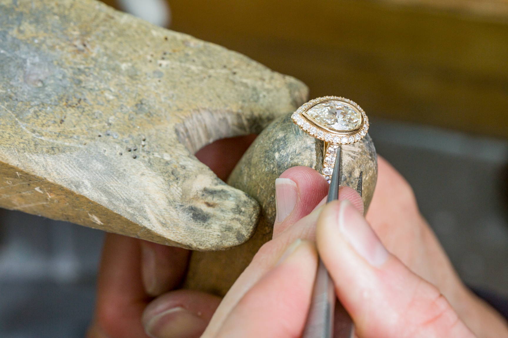 Jeweler inspecting pear cut diamond halo ring and stone integrity.