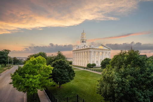 Angled photo fo the Nauvoo Temple facing West. Green trees fill the foreground.