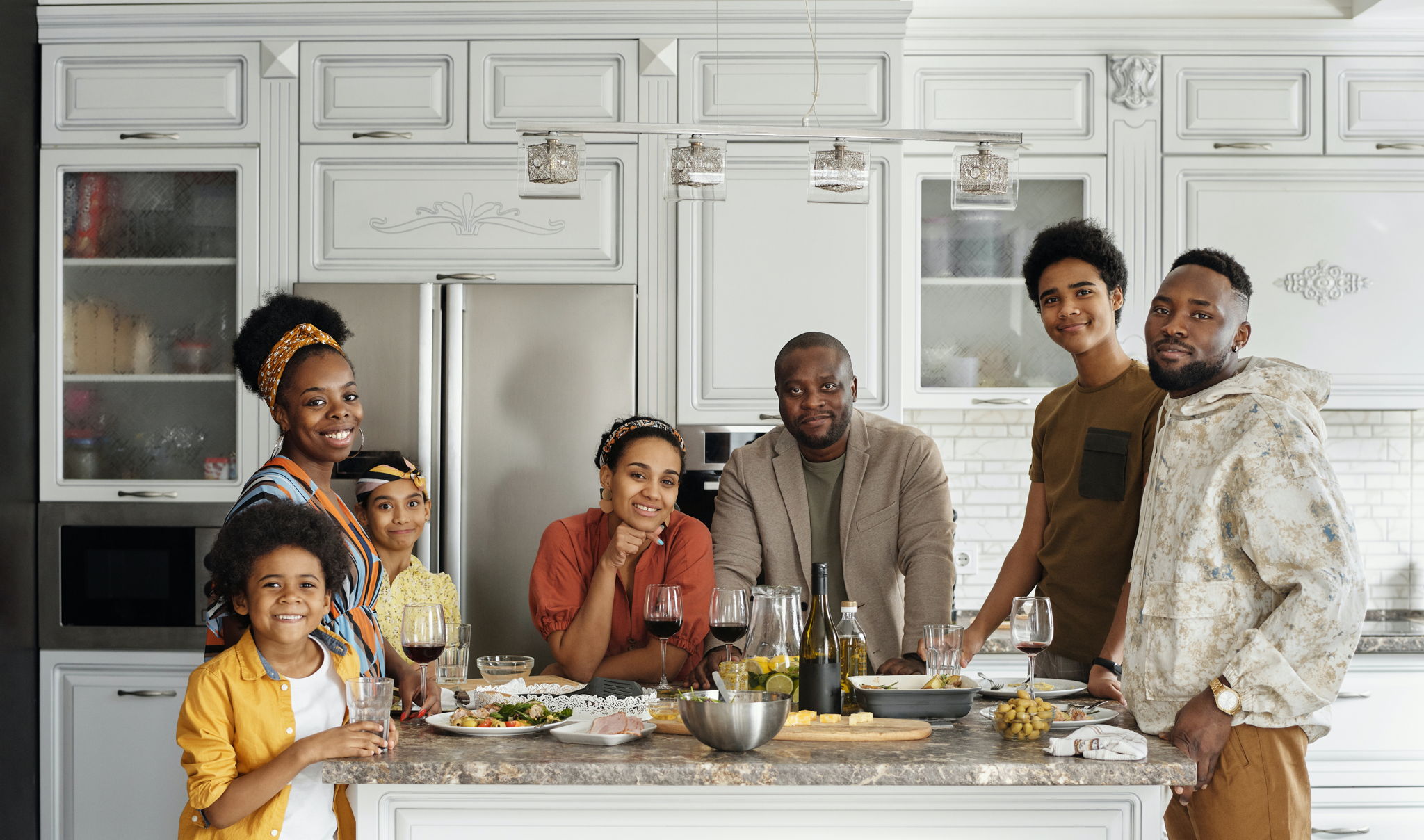 A diverse family of 7 gather around a table getting ready for a holiday dinner