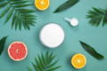 bowl of white collagen powder on teal background surrounded by citrus fruits and ferns