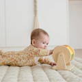 Cute baby spinning a wooden Montessori rattle drum toy.