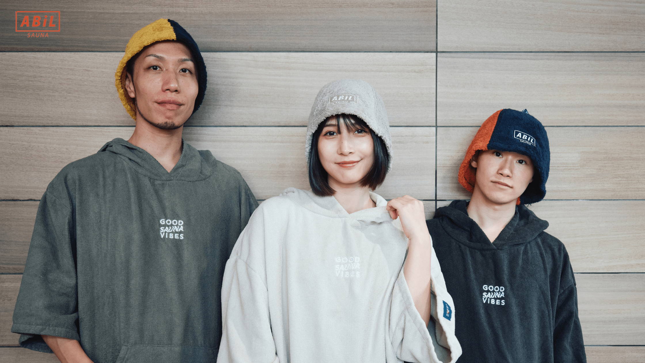 スタイリッシュなサウナポンチョを着て立つモデル女性の全身カット