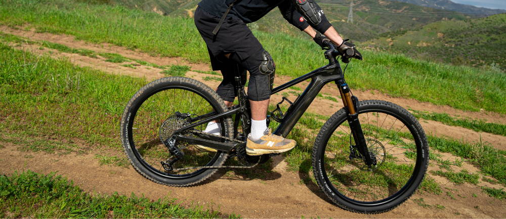 a full suspension mountain bike being ridden on a trail.