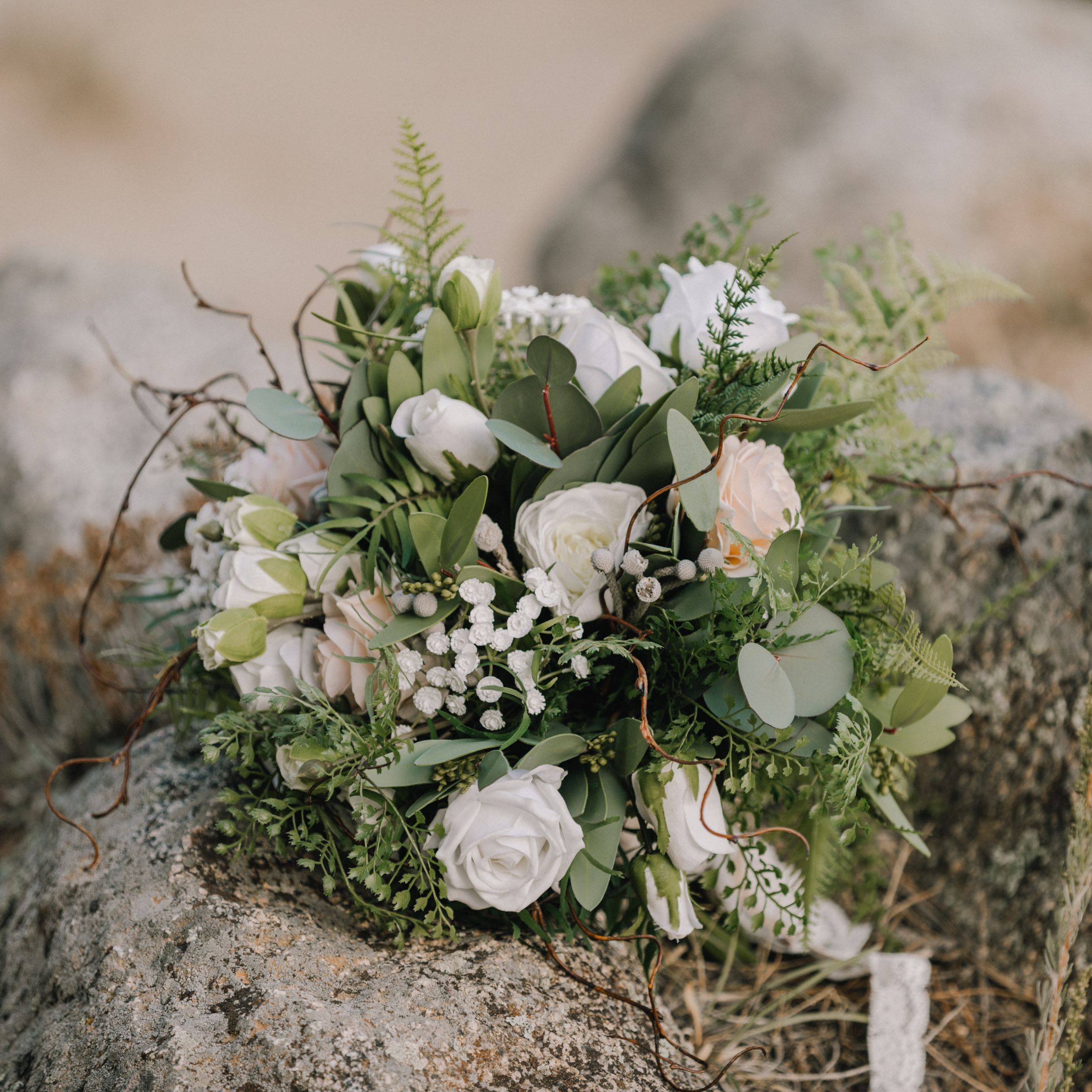 Unstructured bridal bouquet for Colorado mountain wedding with white roses, babies breath, and greenery 