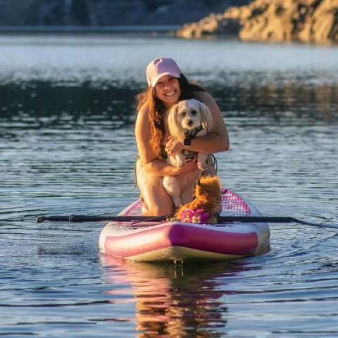 Girl with her dog in inflatable SUP board and have good time