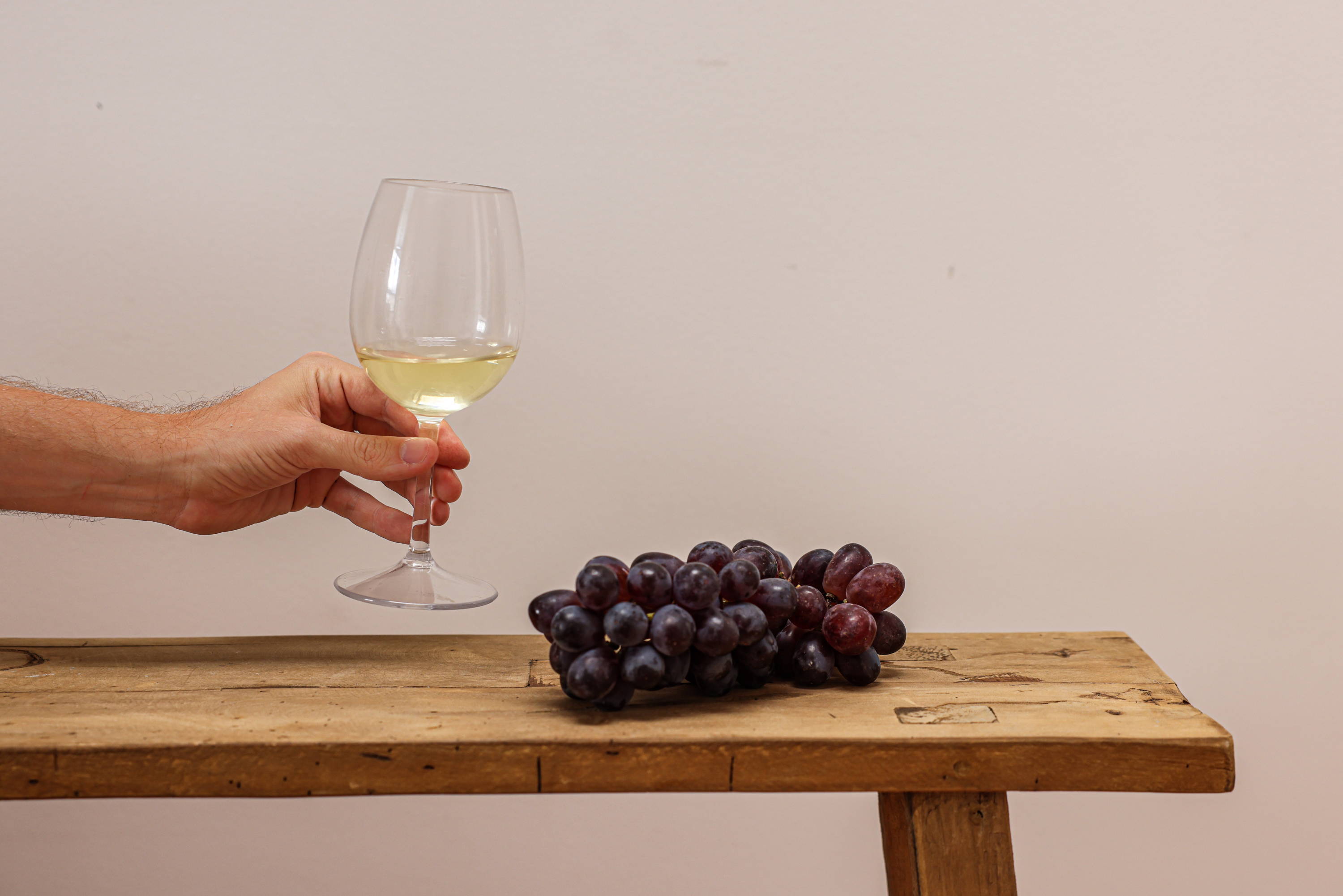 Wooden bench with grapes and a glass of white wine.