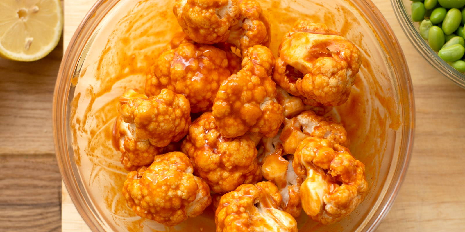 Bowl of cauliflower florets coated in buffalo sauce.