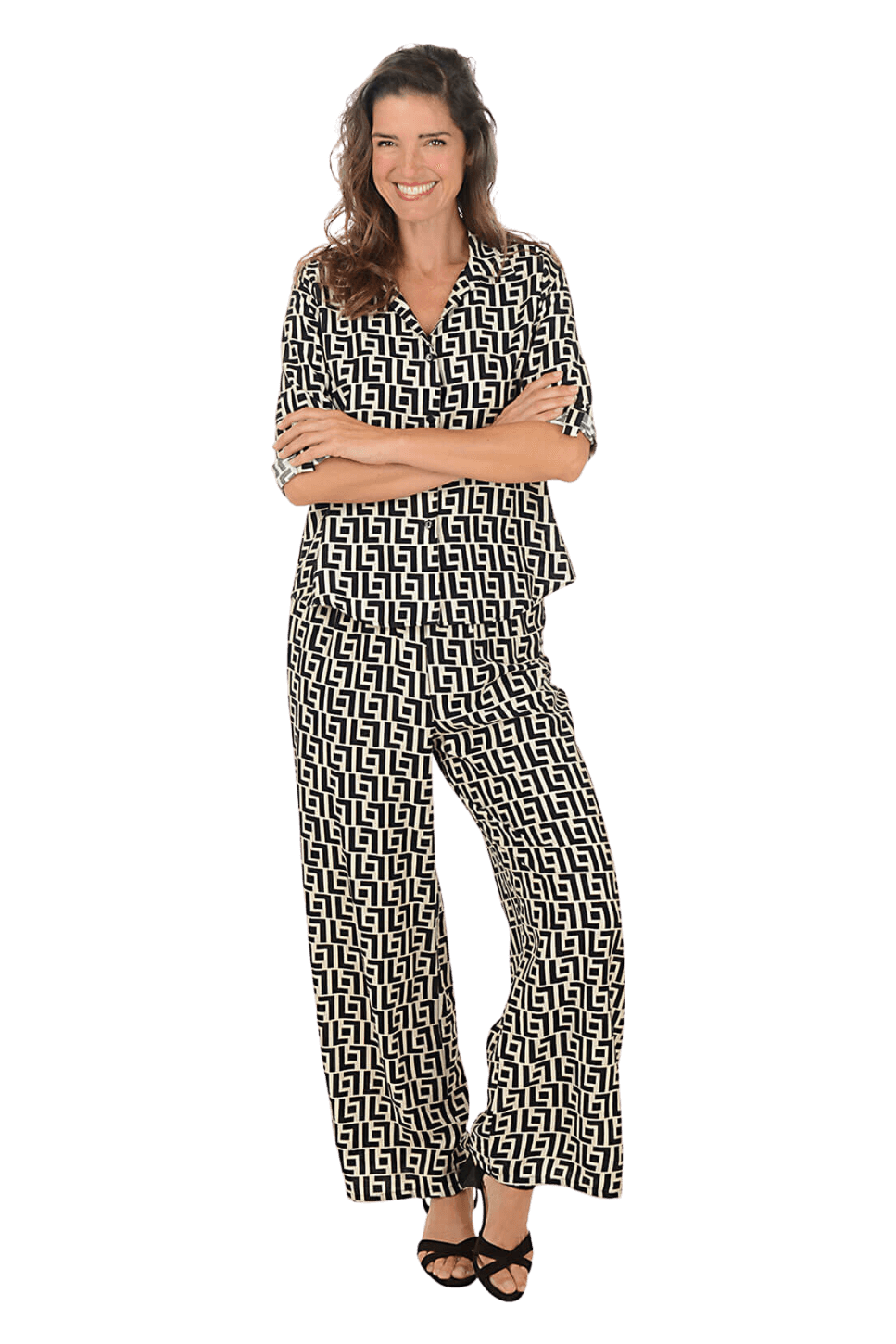 A woman wearing a black and cream printed top and pant coordinating set against a beige background