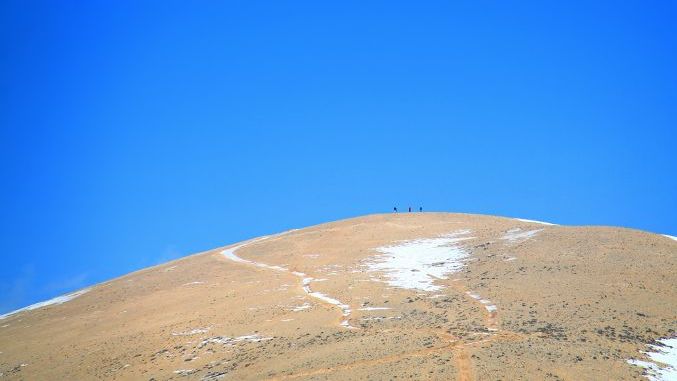 A group of three hikers up a snowy summit in Lebanon.
