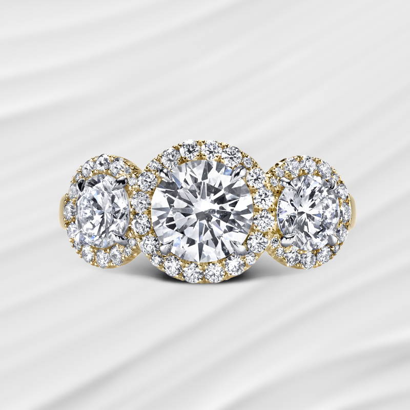 three round brilliant cut diamond ring with accent diamonds in yellow gold.