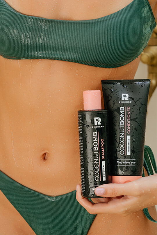 Produkty do włosów Luxury Hair Bundle od ByRokko trzymane przez dziewczynę w zielonym bikini.