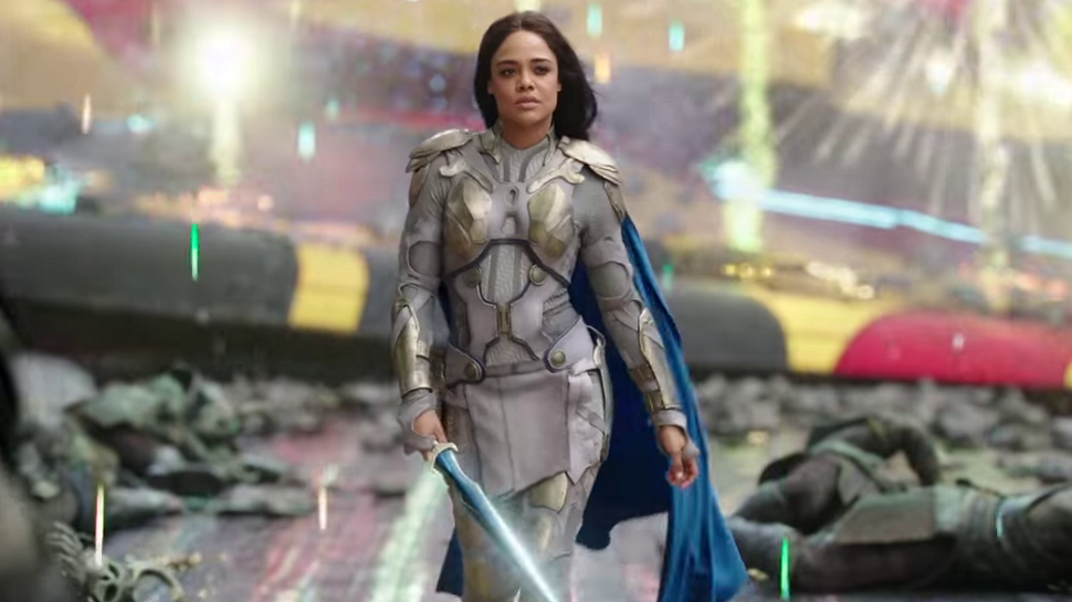 Valkyrie walking confidently in the middle of the battlefield while there are colorful lights and explosions around her.