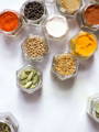 A set of glass spice jars with their lids off, filled with various spices