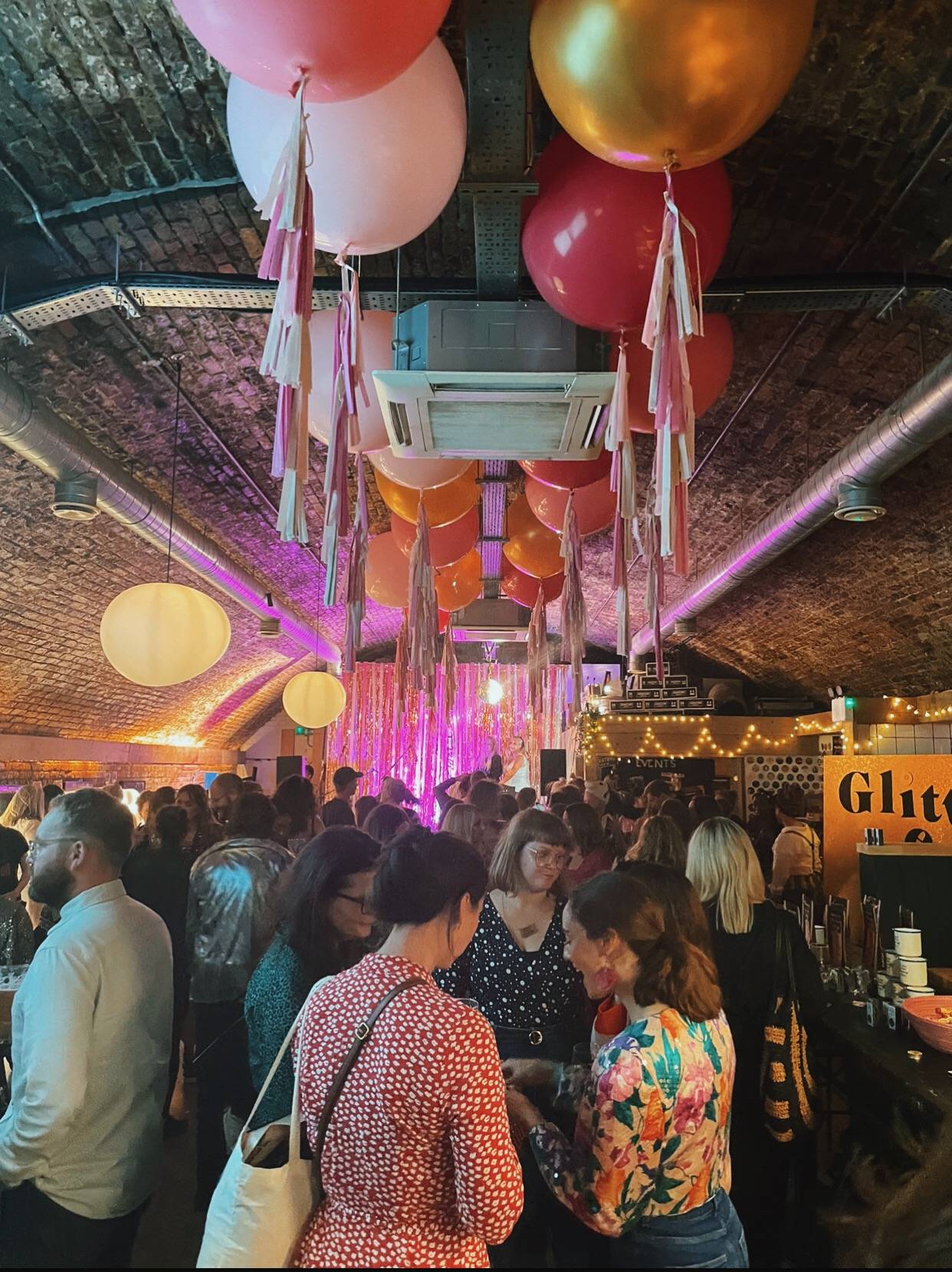 Image shows beautifully decorated venue with balloons, streamers, pink hues, and our biodegradable glitter bar.