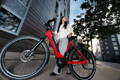 Femme avec son vélo électrique Gazelle rouge en centre ville