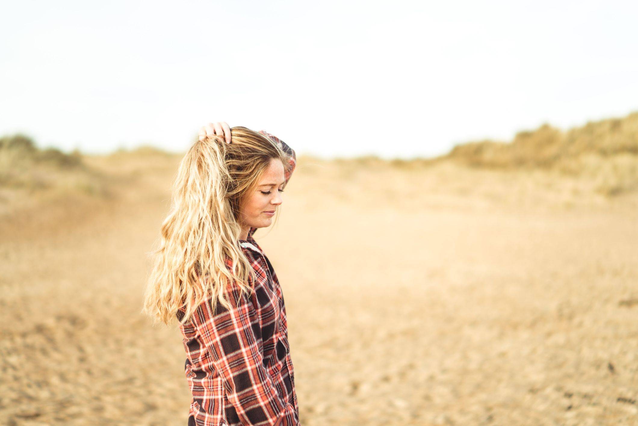 Image of abi walking on beach touching natural wavy hair