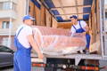 Furniture delivery with couch being safely lifted off delivery truck