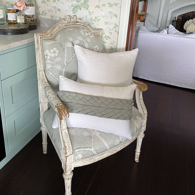 A sage green plaited Luxe Sash featuring on a white oblong cushion which compliments this classic farmhouse nook