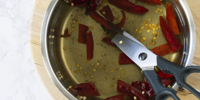 When processing a large number of dried chillies for example, when cooking sambal, you do not need to soak the chillies. Boil them in a pot of water and a splash of vinegar or a piece of tamarind slice. Discard water and rinse chillies after boiling for 3-5 minutes. Optionally, boil the chillies again if the chillies are too spicy. Use a pair of scissors to roughly cut the dried chillies to remove the seeds.