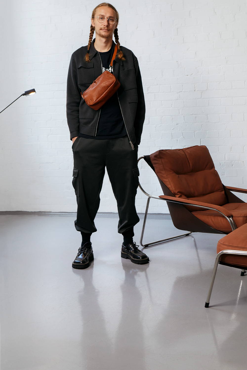 Max Radford with Ally capellino Leila Leather Crossbody standing next to Aram chair