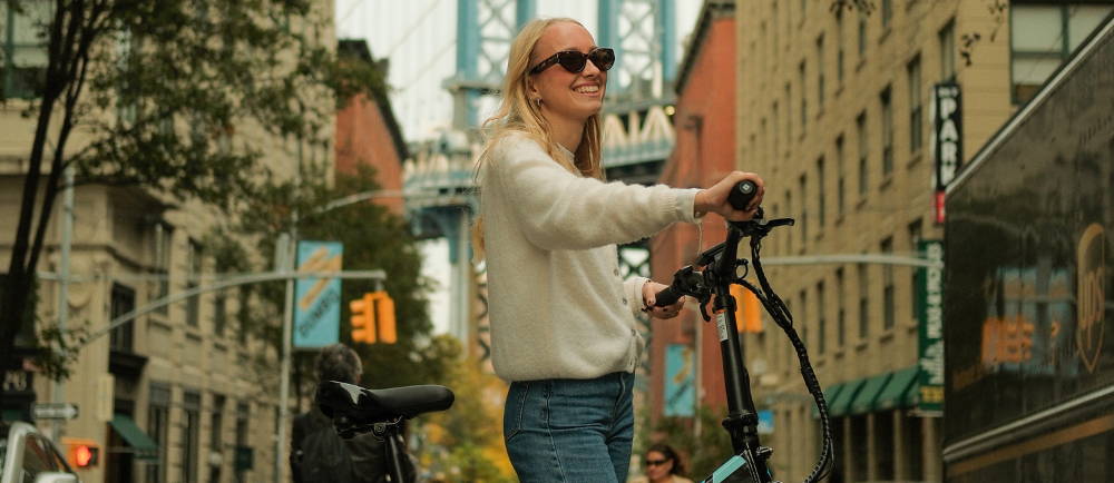 a woman standing over an electric bike in new york city