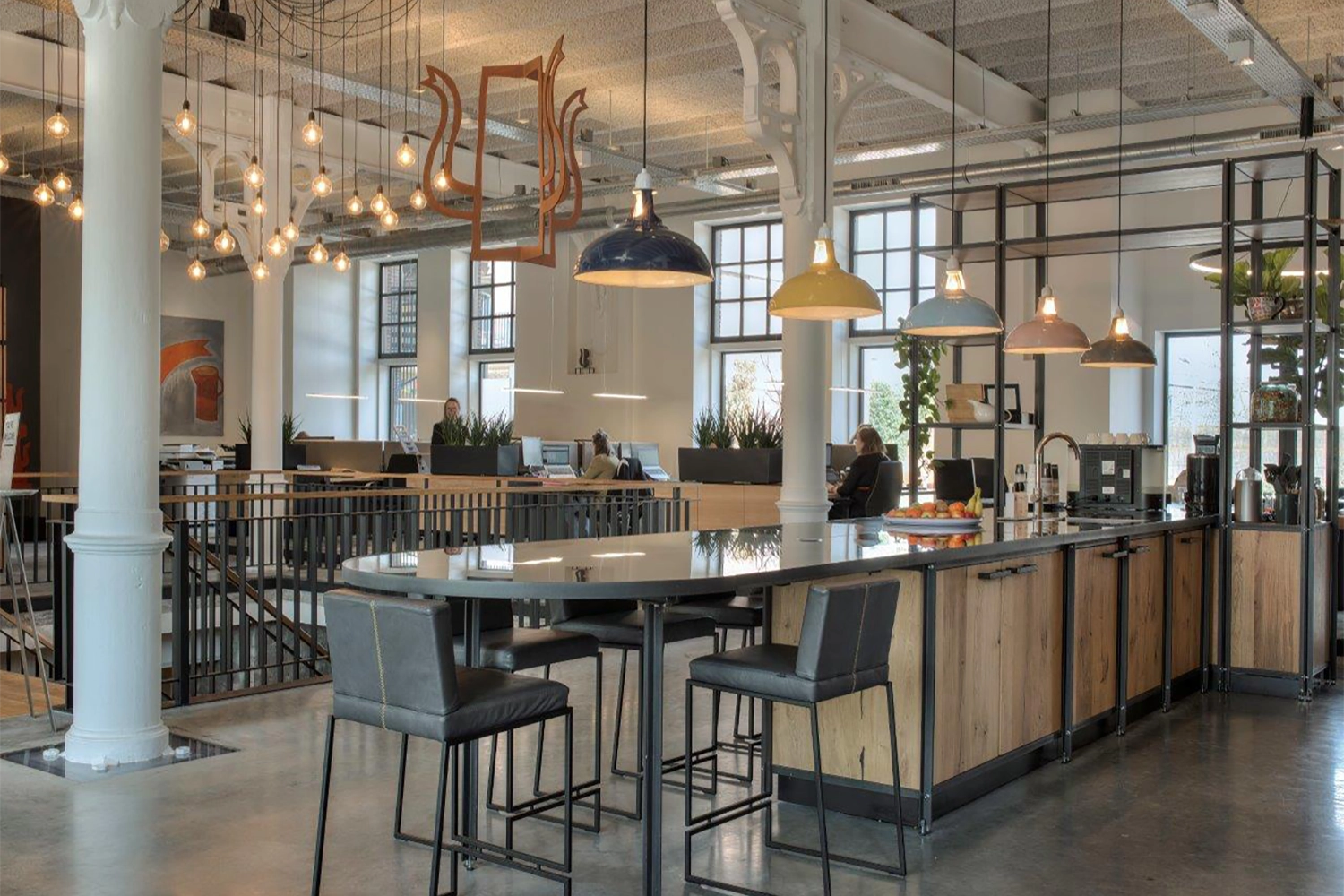 Five Large Coolicon lamps hang over tall table and a kitchen area