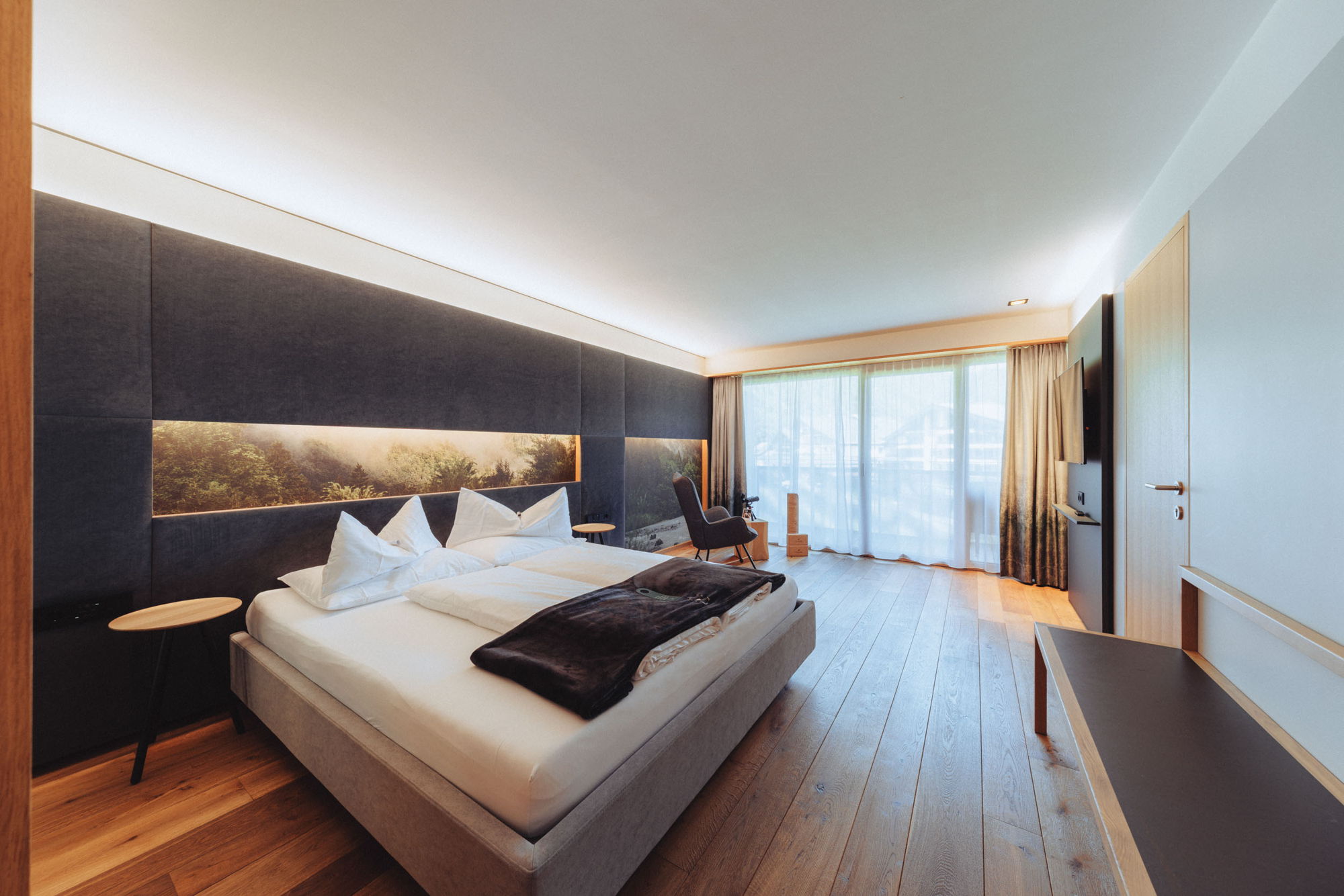 Schlafbereich der Feel good Suite im Hotel Sonne Mellau mit Doppelbett und modernem Design