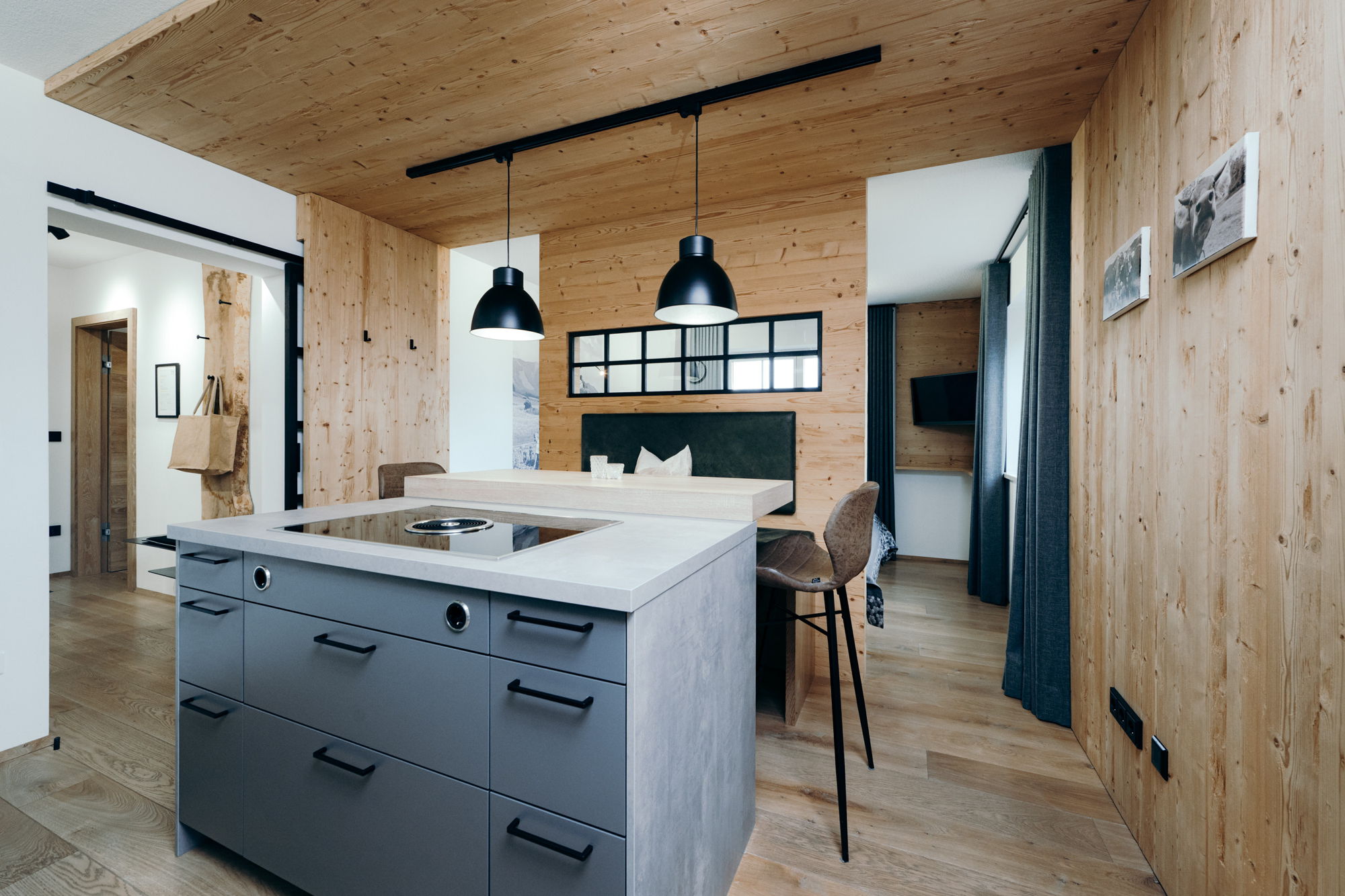 Im Vordergrund ein Arbeitsbereich der Küche, im Hintergrund ein mit Holz verkleideter Essbereich.