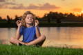 Little girl meditating next to a lake.