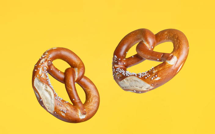 Traditional German salted pretzels floating against a yellow background (preview)