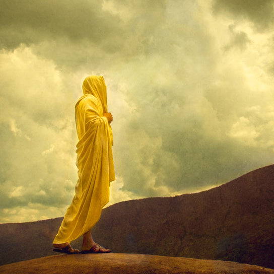 Jesus walking along the hills wearing a yellow robe.