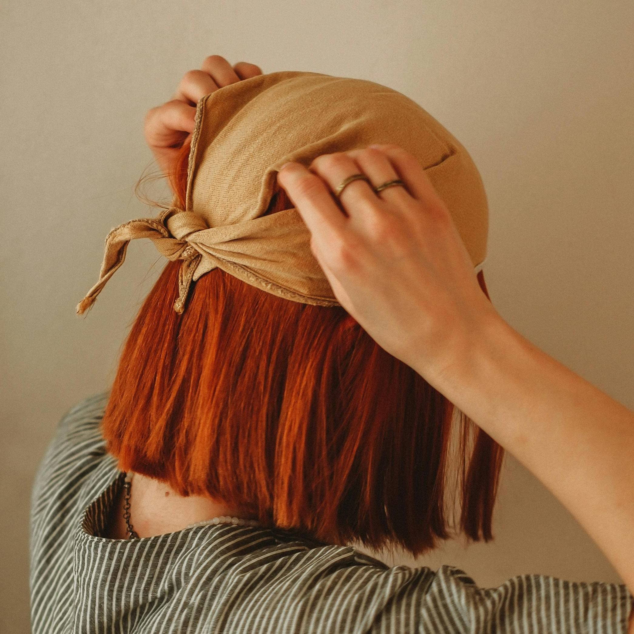 back of woman tying a scarf over her hair