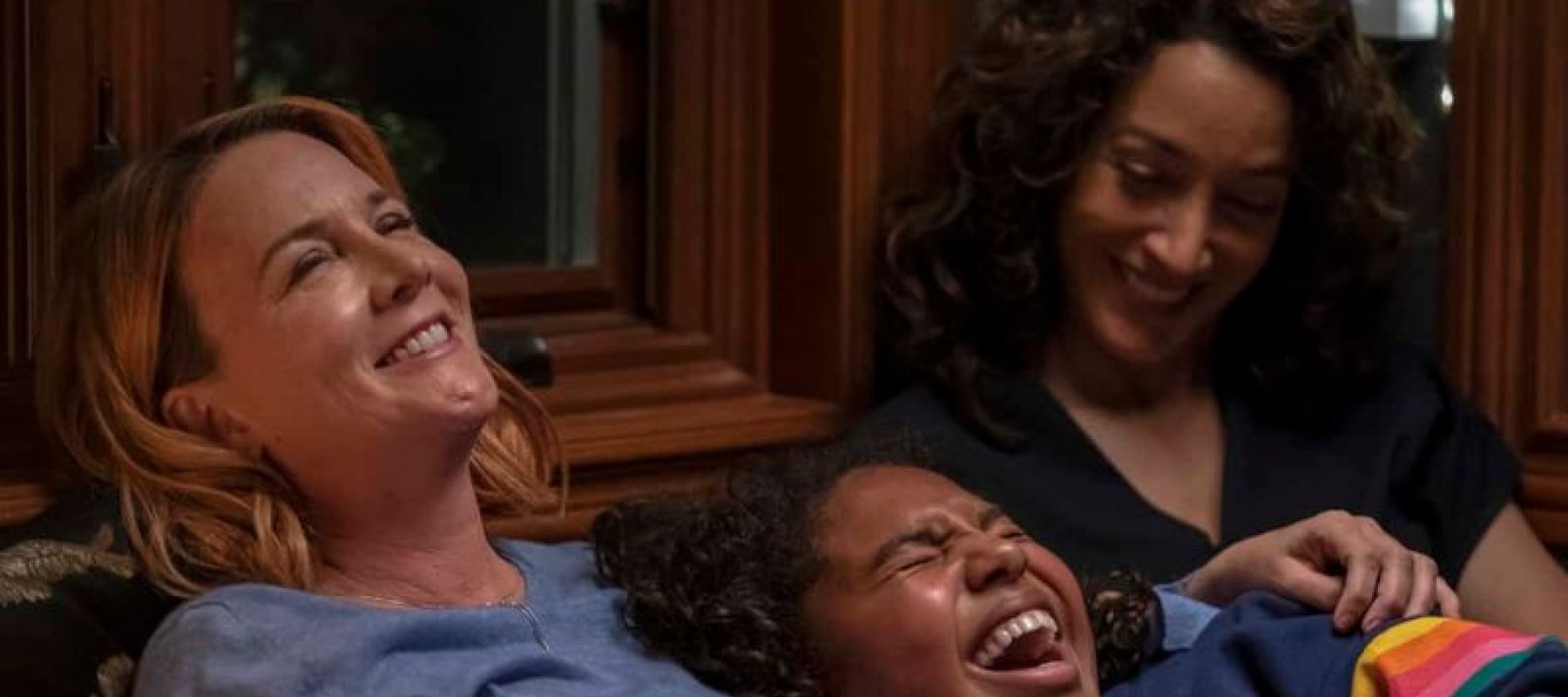 Alice and two multi ethnic friends laying next to eachother laughing and smiling at a joke.