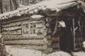 a log cabin covered in snow with a pack hanging at the door