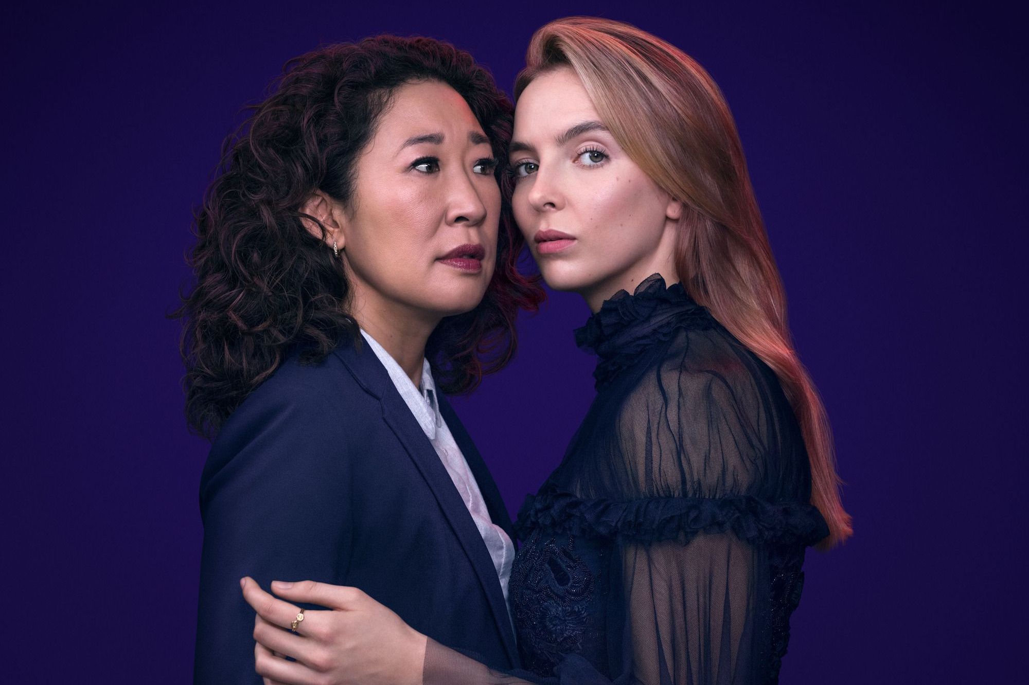 Villanelle and Eve holding eachother while Villanelle is looking at the camera in a purple background.