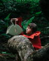 White female model lying on a giant log with a NOIRANCA handbag Alice in Olive Green
