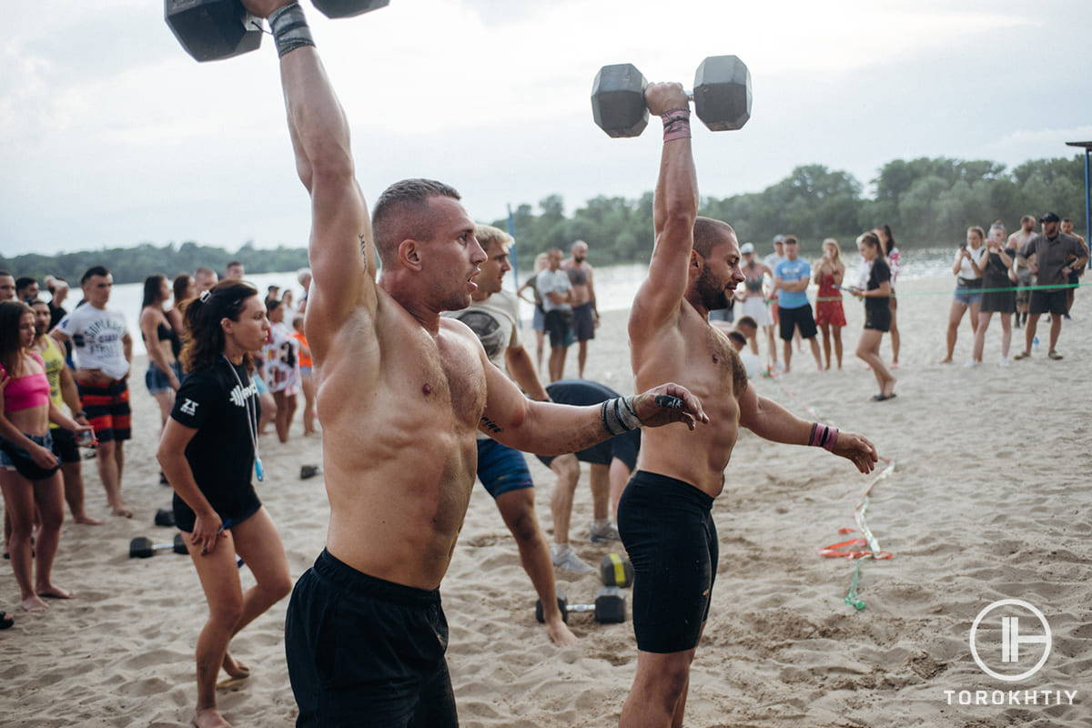 athletes with dumbbells on beach