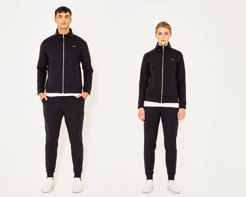 Man and woman wearing matching black zip up track jackets in black and sweatpants from sustainable streetwear brand Riley Studio